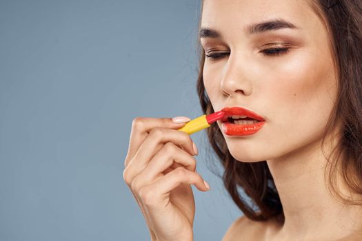 Woman with lipstick on a gray background brunette makeup with eye shadow on the eyelids. High quality photo