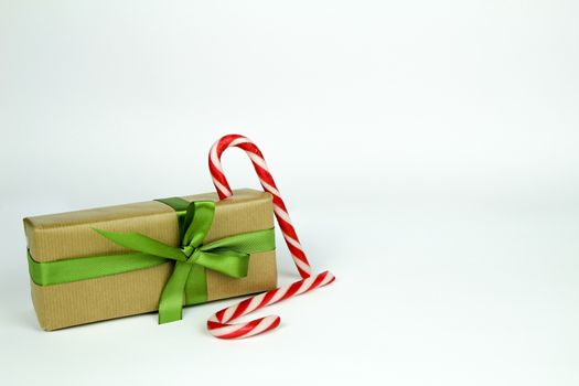Gifts wrapped with brown and red paper and green bows next to Christmas decoration on white background