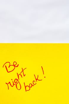 Be right back handwriting text close up isolated on orange paper with copy space. Writing text on memo post reminder