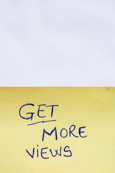 Get more views handwriting text close up isolated on yellow paper with copy space.