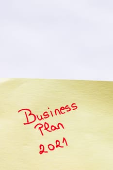 Business plan 2021 handwriting text close up isolated on yellow paper with copy space.