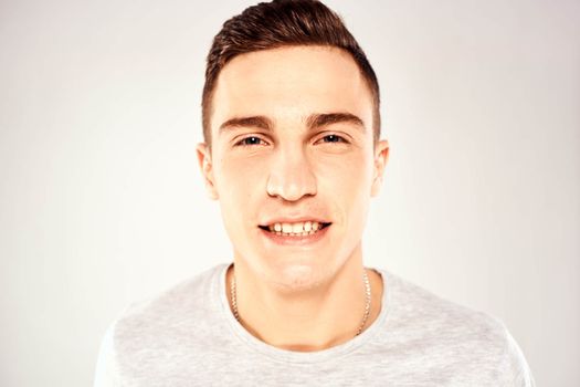 Man in a white t-shirt emotions gestures with hands close-up cropped view light background. High quality photo