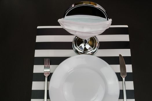 Setting a dish at a table on eating alone before a mirror with covid-19 protection mask, encouraging safety guidelines practices.