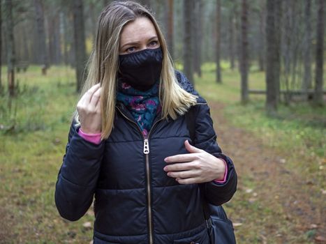 Beautiful european Women Wearing Protective Mask Outside Pretty young girl in medical black face mask in a forest. covid19 concept. modern reality. copy space. 2020, allergy. Autumn season. Copy space