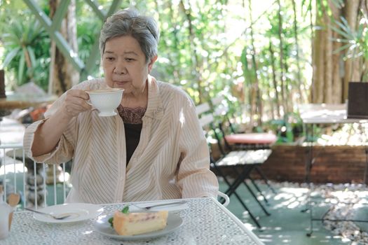 old elderly senior elder woman drinking hot mocha coffee tea at restaurant. mature retirement lifestyle