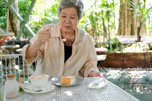 old asian elderly senior elder woman eating cheesecake at restaurant. mature retirement lifestyle