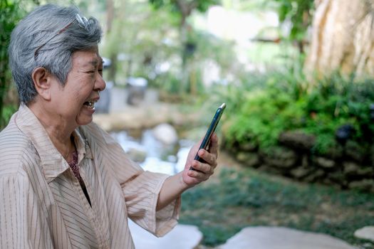 sad upset asian old asian elderly senior elder woman talking on video call on smart mobile phone