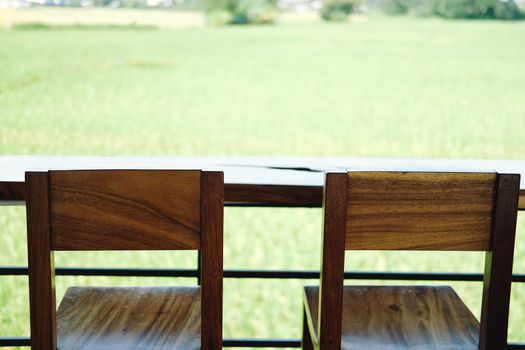 wooden chair on terrace with green rice paddy field view