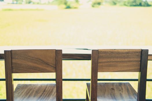 wooden chair on terrace with green rice paddy field view