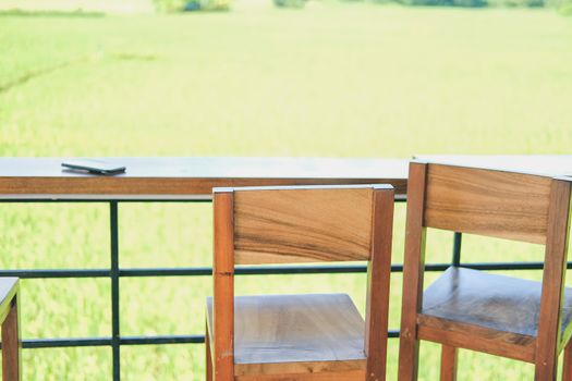wooden chair on terrace with green rice paddy field view