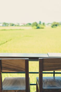 wooden chair on terrace with green rice paddy field view