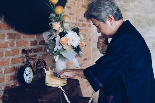 old asian elderly senior elder woman dialing telephone number at home