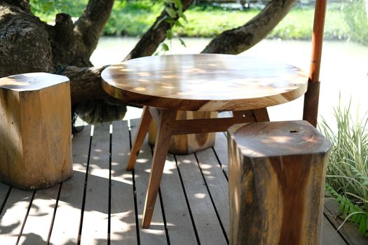 wooden stool & table on terrace near pond at cafe restaurant