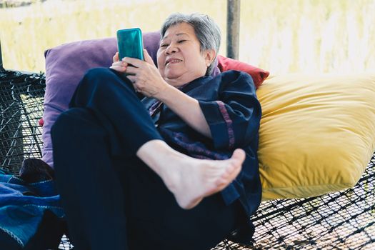 asian elder senior woman using mobile smart phone. elderly female holding cellphone. mature retirement lifestyle