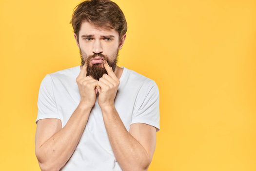 Bearded man emotions gestures with hands facial expression white t-shirt yellow background. High quality photo