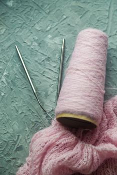 Knitting background flatlay. Bobbin of pink yarn, knitting needles, a knitted pullover on a concrete background, top view. Background about needlework and handicrafts, copy space