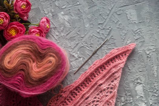 Crochet background flatlay. Bobbin of colored yarn, crochet hook, crochet scarf on a concrete background, top view. Background about needlework and handicrafts, copy space