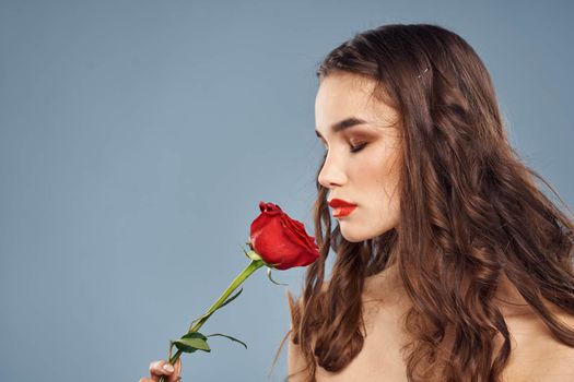 woman with a rose in her hands naked shoulders evening makeup red lips. High quality photo