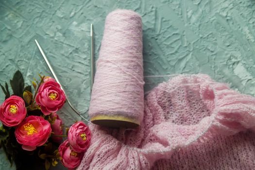 Knitting background flatlay. Bobbin of pink yarn, knitting needles, a knitted pullover on a concrete background, top view. Background about needlework and handicrafts, copy space