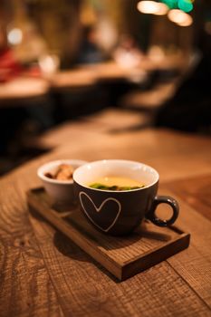 Serving cream soup in a cup with a cup of rusks on a wooden tray.