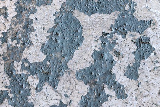 Detailed and colorful close up at cracked and peeling paint on concrete wall textures in high resolution.
