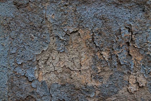 Detailed and colorful close up at cracked and peeling paint on concrete wall textures in high resolution.