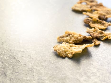 A group of corn flakes on a gray floor. Daily breakfast and nutrition