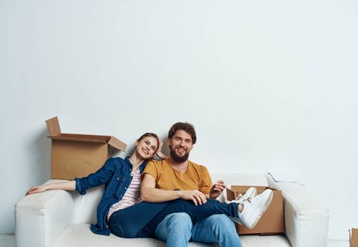 Man and woman sit on white couch boxes with moving lifestyle things. High quality photo