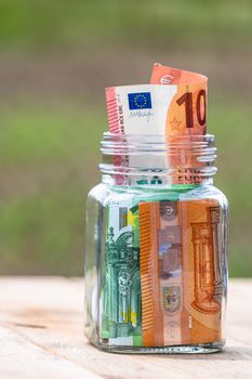 Composition with saving money banknotes in a glass jar. Concept of investing and keeping money, close up isolated.