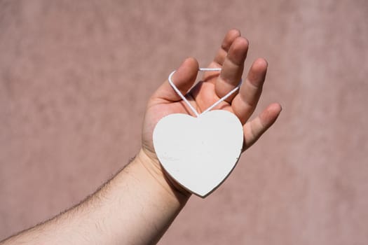 Hands holding a white wooden heart shaped object decoration isolated with copy space. Empty space template for your text.