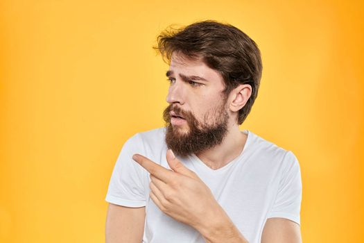 A man in a white t-shirt gestures with his hands studio lifestyle yellow background emotions. High quality photo