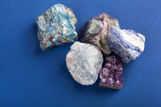 set of close up Natural minerals, precious stones on classic blue background. Use for jewelry. Space for text.