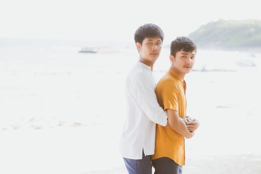 Homosexual portrait young asian couple standing hug together on beach in summer, asia gay going tourism for leisure and relax with romantic and happiness in vacation at sea, LGBT concept.