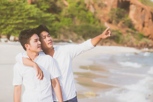 Homosexual portrait young asian couple standing pointing something together on beach in summer, asia gay going sea for leisure with romantic and happy in vacation at sea, LGBT with legal concept.