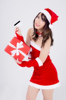 Beautiful portrait young asian woman happy holding credit card and red gift box in Christmas holiday isolated on white background, beauty asia girl surprise shopping with credit card in xmas day.