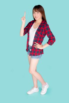 Beautiful portrait young asian woman smiling gesture pointing something and excited summer holiday isolated blue background, asia girl confident and cheerful with journey, travel concept.