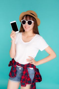 Beautiful young asian woman showing smart mobile phone for presenting something in travel summer trip in vacation isolated on blue background, asia girl holding smartphone, holiday concept.