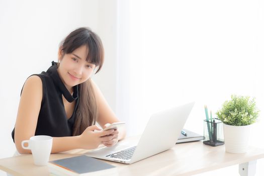 Beautiful young asian woman working laptop computer online to internet and texting message on smart mobile phone, freelance using notebook, business and communication concept.