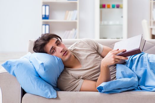 Young student man preparing for college exams in bed with book