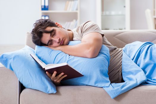 Young student man preparing for college exams in bed with book