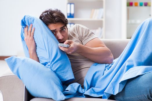 Man watching tv from bed holding remote control unit
