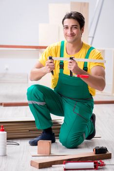 Contractor working on laminate wooden floor 