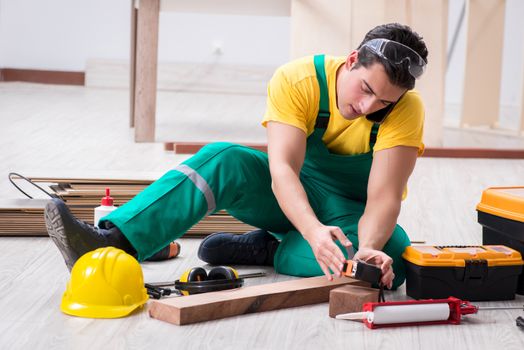 Contractor working on laminate wooden floor 
