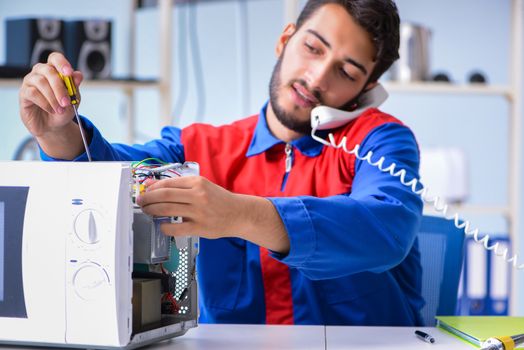 Young repairman fixing and repairing microwave oven