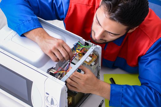 Young repairman fixing and repairing microwave oven