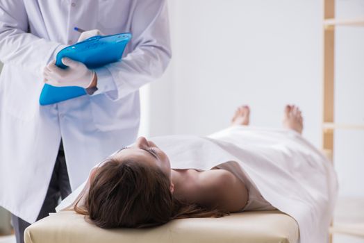 Police coroner examining dead body corpse in morgue