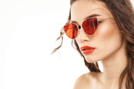 Portrait of brunette woman in sunglasses naked shoulders light background. High quality photo