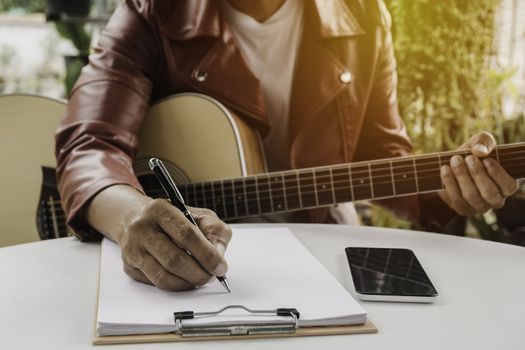 A Song writer holding pen for compose a song. Musician playing acoustic guitar. Live music and abstract musical concept.