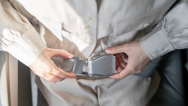 Close up of women fasten seat belt on the airplane.