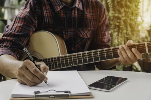 A Song writer holding pen for compose a song. Musician playing acoustic guitar. Live music and abstract musical concept.